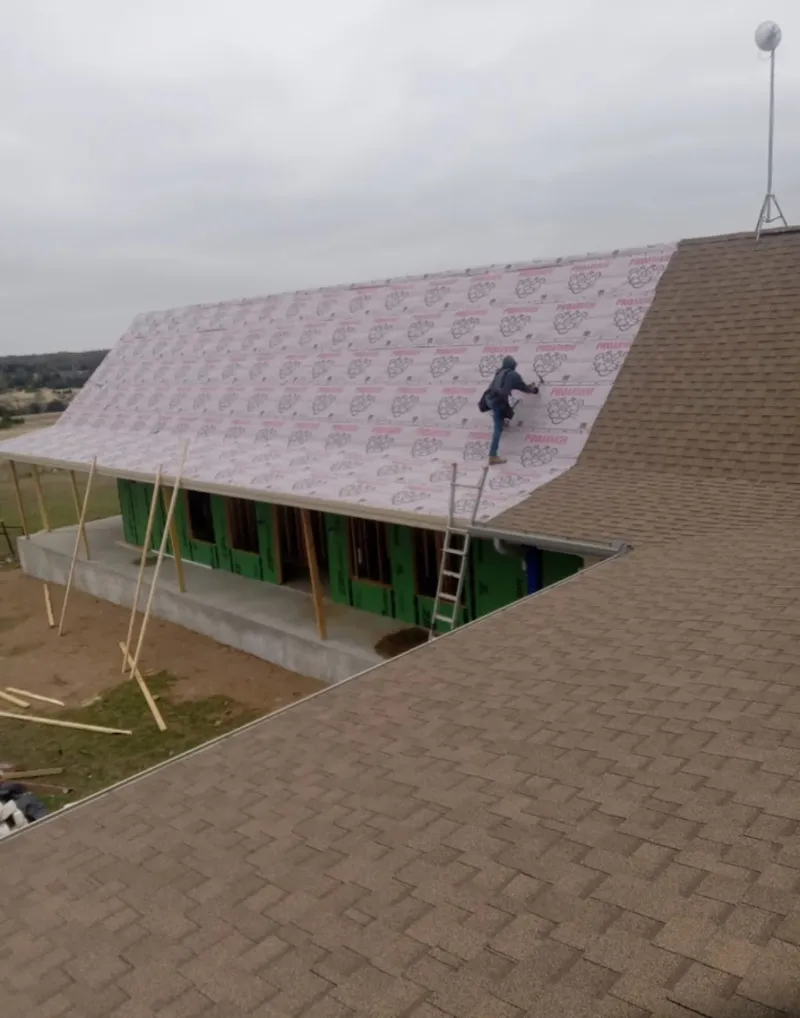 Worker preparing underlayment for a metal roof installation in Wauwatosa